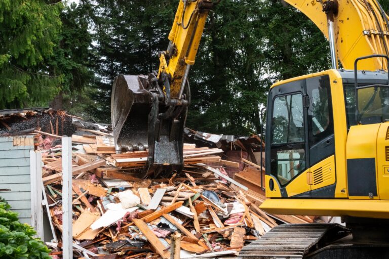 Demolition of old wood frame house using a large excavator machine with jawbone bucket