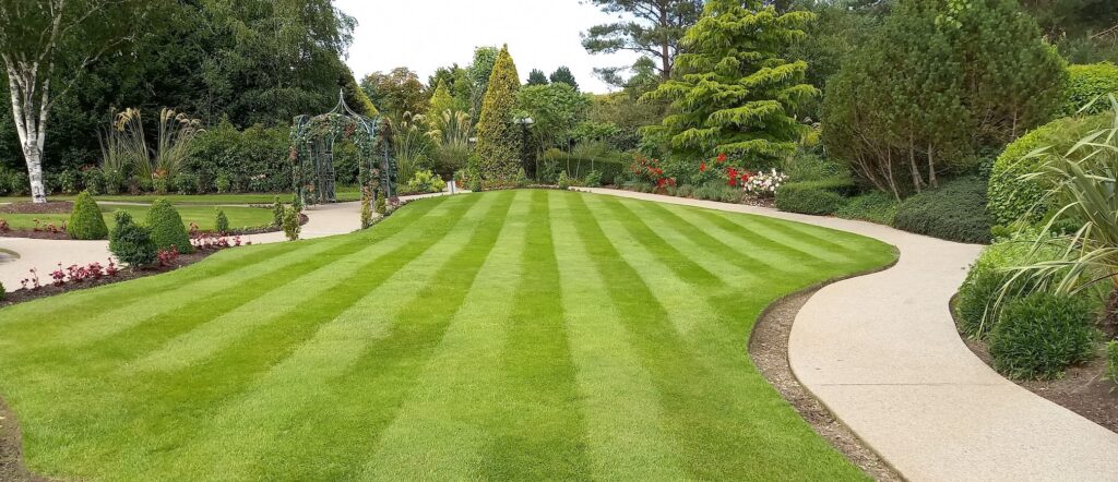 Striped lawn with trees paths and arch in large garden